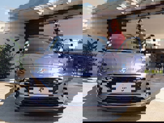 Kvinde står i døren, på vej til at stige ind i en lilla Hyundai i10