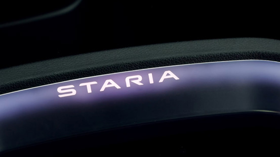 Nærbillede af det oplyste Staria-logo på en mørk, buet biloverflade.