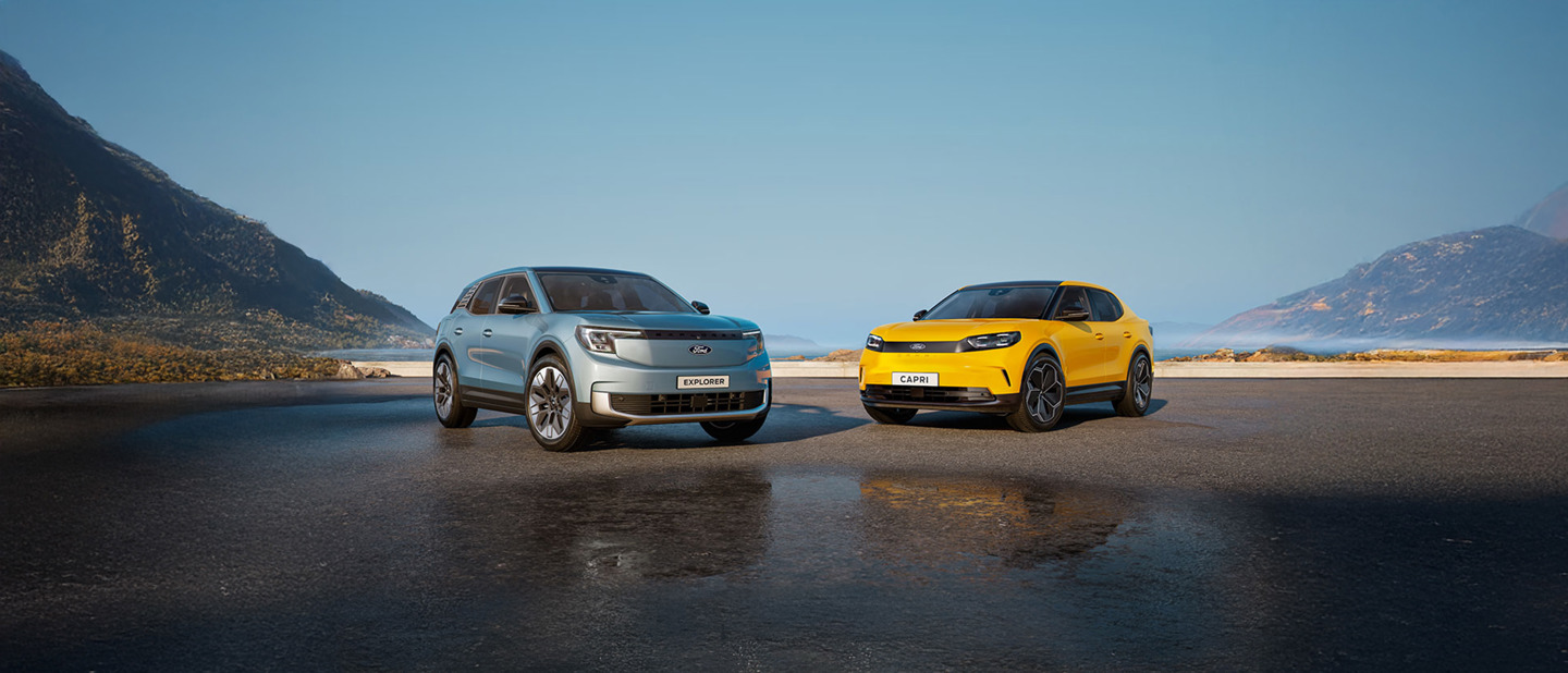 To Citroën SUV'er, en blå og en gul, parkeret på en åben vej med bjerge og en diset blå himmel i baggrunden.