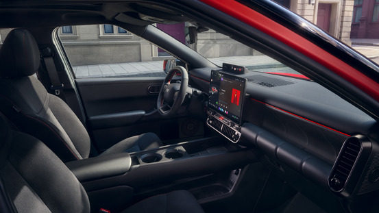 Interiøret i en moderne IONIQ 3 med mørke sæder, et digitalt instrumentbræt, en touch-skærm og røde detaljer.