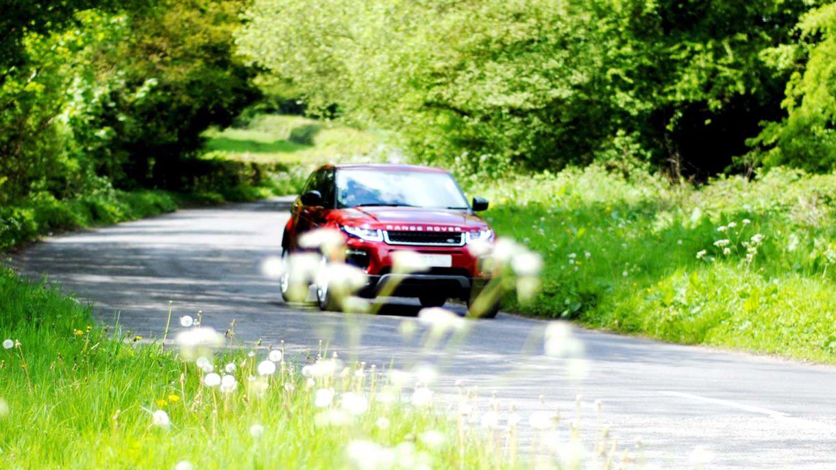 Rød Range Rover kørende i grønt område