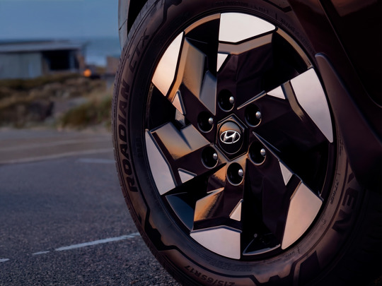 Nærbillede af et Hyundai-bilhjul med geometrisk alufælgdesign og Roadian GTX-dæk, parkeret på en asfaltvej.