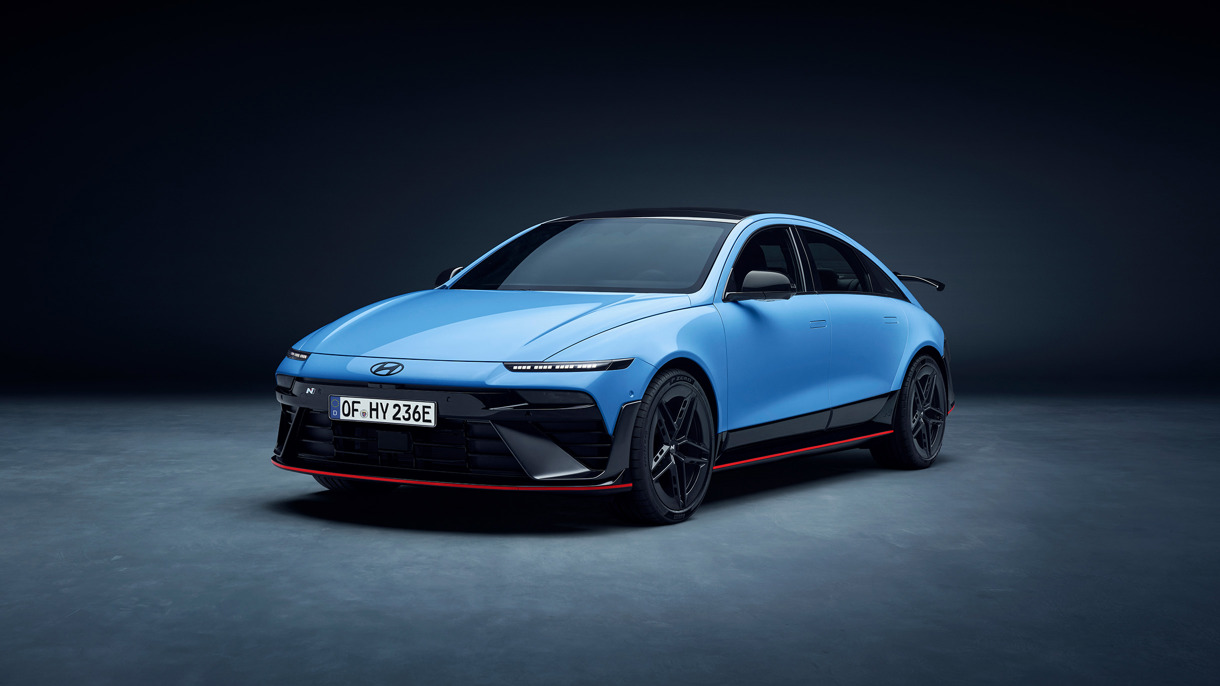 En blå Hyundai Ioniq 6 elektrisk sedan parkeret i et mørkt studie, med røde detaljer og sorte hjul.